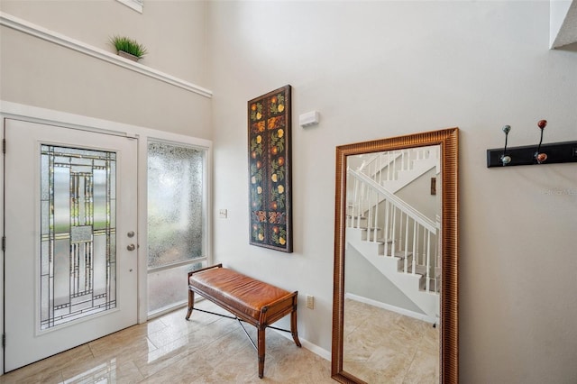 entryway featuring a high ceiling, stairway, and baseboards