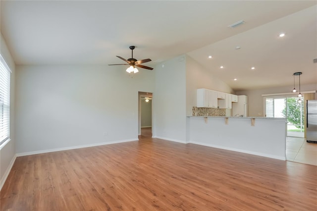 unfurnished living room with high vaulted ceiling, light hardwood / wood-style flooring, and ceiling fan