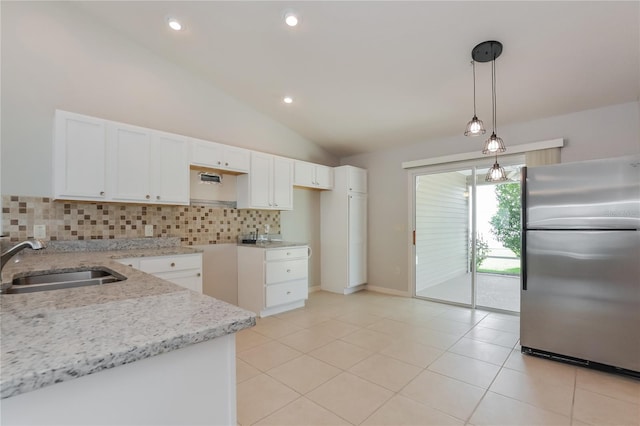 kitchen featuring lofted ceiling, pendant lighting, sink, stainless steel refrigerator, and white cabinetry