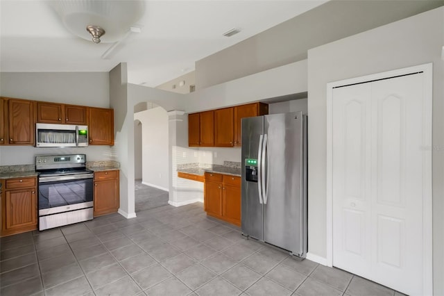 kitchen featuring light tile patterned floors, high vaulted ceiling, stainless steel appliances, and ornate columns