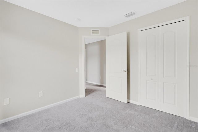 unfurnished bedroom featuring light carpet and a closet