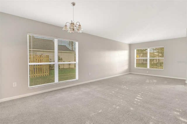 carpeted empty room featuring a chandelier