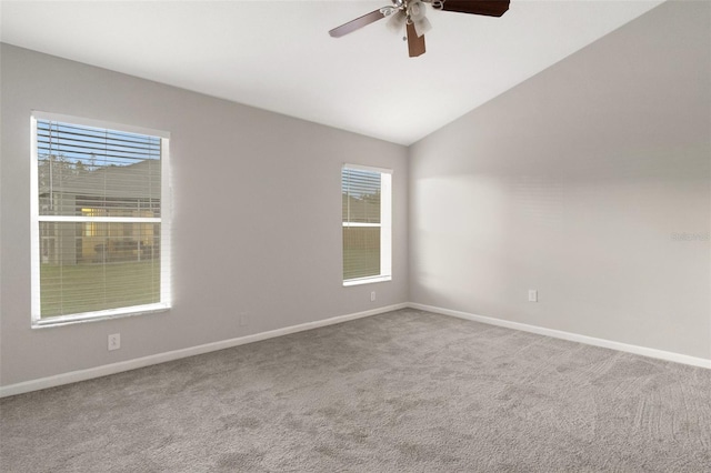 carpeted spare room featuring plenty of natural light, ceiling fan, and lofted ceiling