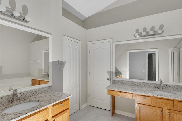 bathroom with tile patterned floors, vanity, a tub to relax in, and vaulted ceiling