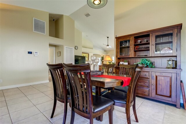 tiled dining room featuring high vaulted ceiling