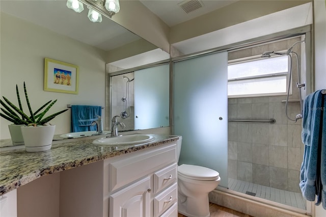 bathroom with vanity, toilet, and a shower with door