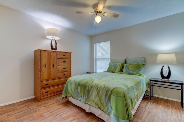 bedroom with ceiling fan, a textured ceiling, and light wood-type flooring