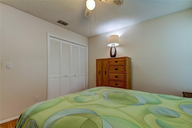 bedroom with ceiling fan, hardwood / wood-style flooring, a closet, and a textured ceiling