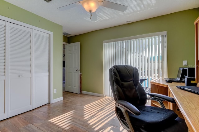 office area with a textured ceiling, ceiling fan, and light wood-type flooring