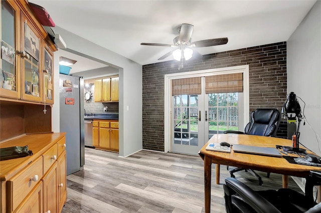 home office featuring french doors, light wood-type flooring, ceiling fan, and brick wall