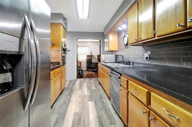 kitchen with tasteful backsplash, sink, stainless steel appliances, and light wood-type flooring