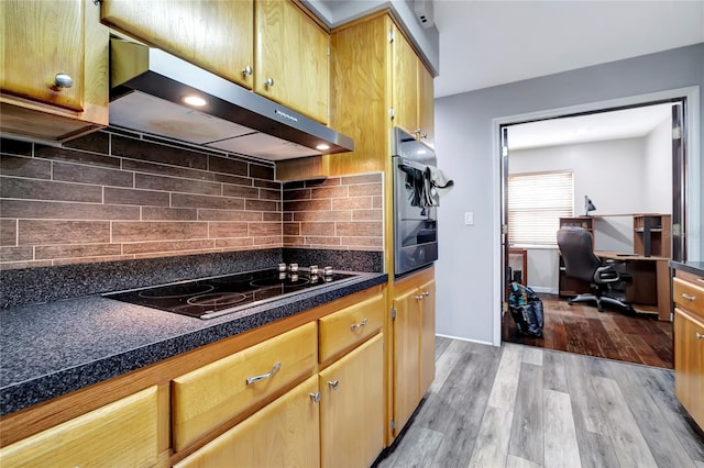 kitchen with stainless steel oven, tasteful backsplash, black electric cooktop, and light hardwood / wood-style flooring