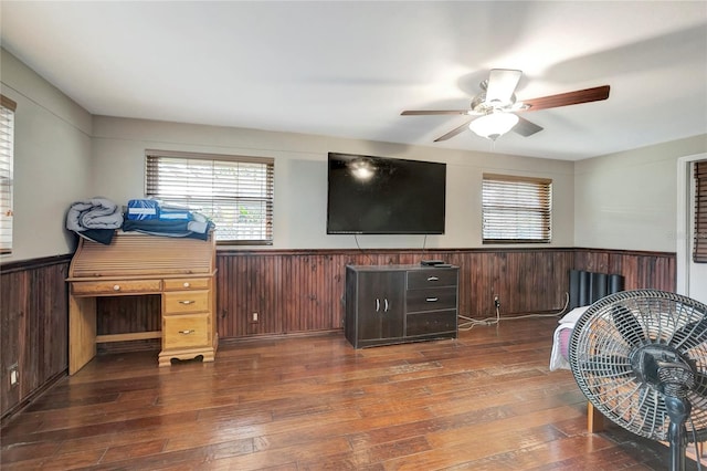 living room with ceiling fan, dark wood-type flooring, and wood walls