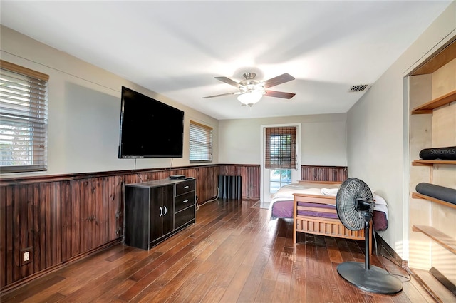 living room featuring dark hardwood / wood-style flooring, ceiling fan, and wooden walls