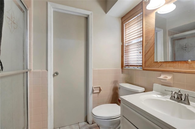 bathroom with tile patterned floors, walk in shower, vanity, tile walls, and toilet