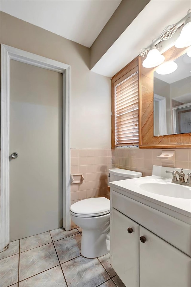 bathroom featuring tile patterned flooring, vanity, toilet, and tile walls