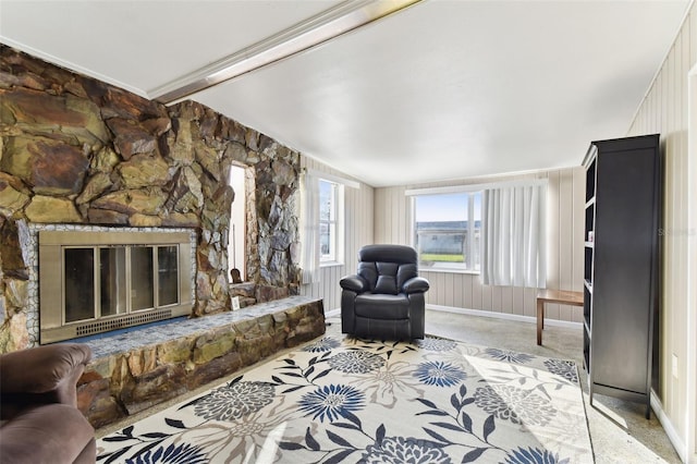 carpeted living room featuring a stone fireplace and vaulted ceiling