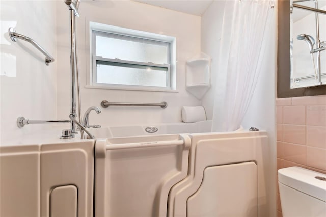 bathroom featuring tile walls and toilet