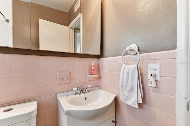 bathroom with tile walls, vanity, tasteful backsplash, and toilet