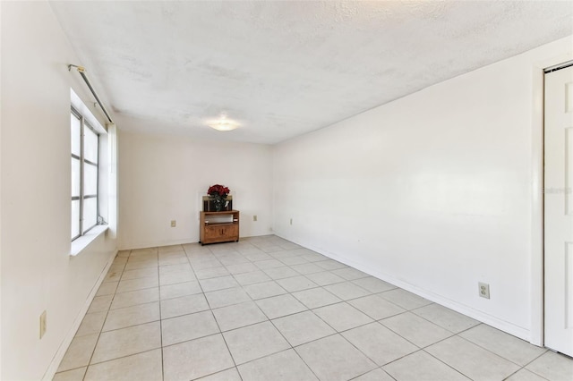 spare room featuring a textured ceiling and light tile patterned flooring