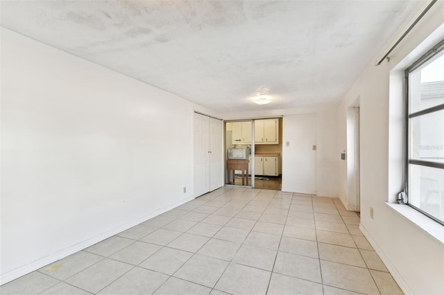 spare room with a textured ceiling and light tile patterned floors