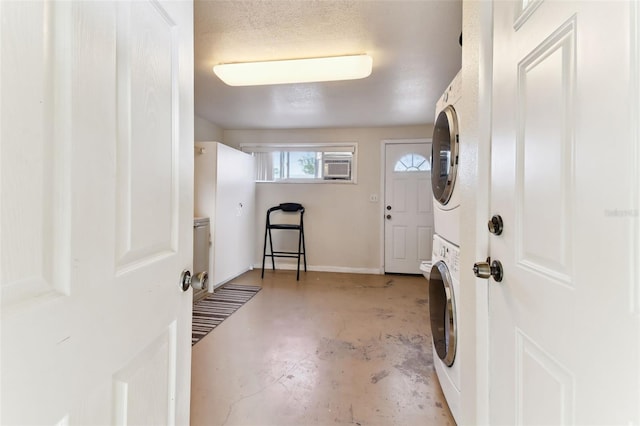 laundry area with a textured ceiling and stacked washer / drying machine