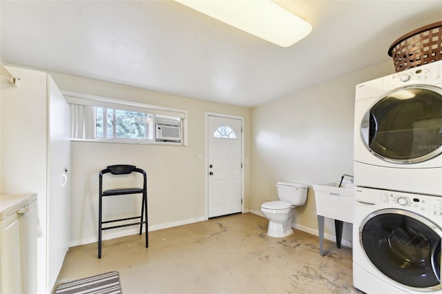 clothes washing area with stacked washer and clothes dryer, sink, and a wall mounted air conditioner