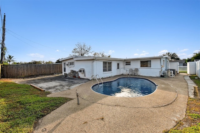 back of property with a fenced in pool and a patio