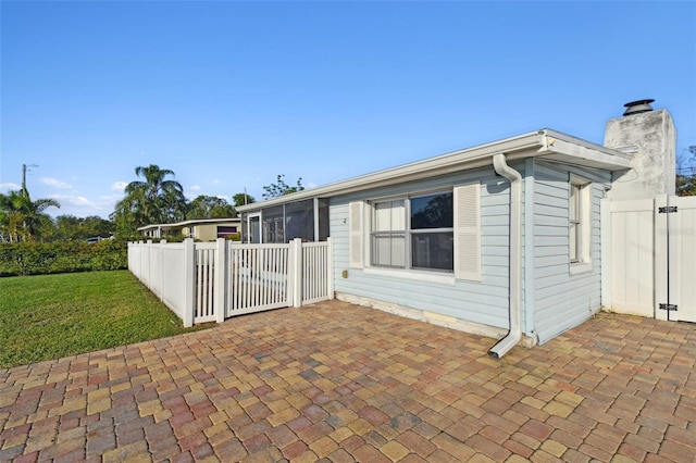 exterior space featuring a patio, a sunroom, and a front lawn