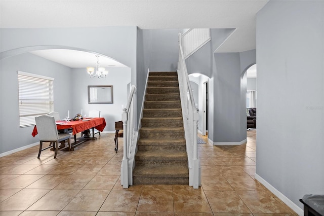 stairs featuring tile patterned flooring and a notable chandelier