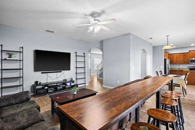 tiled living room with ceiling fan and a textured ceiling