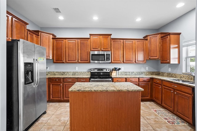 kitchen with a center island, light tile patterned floors, sink, light stone countertops, and appliances with stainless steel finishes