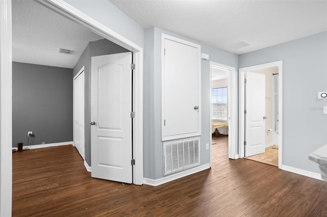 hallway with dark wood-type flooring and a textured ceiling