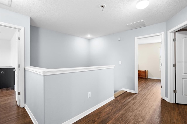 hallway with dark wood-type flooring and a textured ceiling