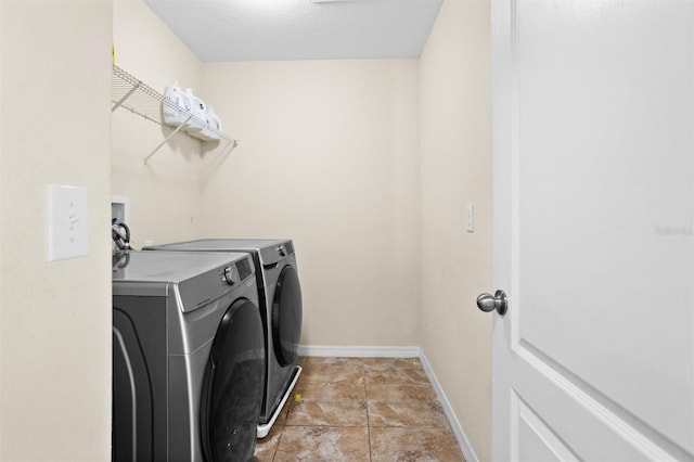 laundry area featuring washing machine and clothes dryer, light tile patterned flooring, and a textured ceiling