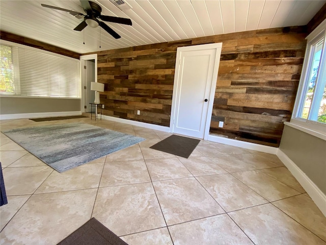 tiled empty room with ceiling fan, wood ceiling, and wooden walls