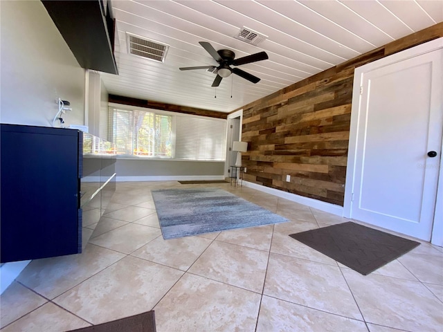 interior space with wooden walls, light tile patterned floors, wood ceiling, and ceiling fan