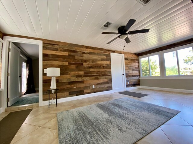 living room featuring wooden walls, light tile patterned floors, wooden ceiling, and ceiling fan