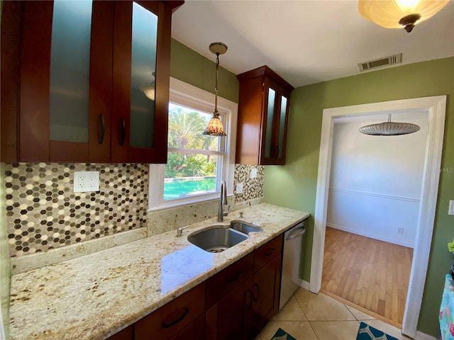 kitchen with dishwasher, sink, hanging light fixtures, decorative backsplash, and light stone countertops