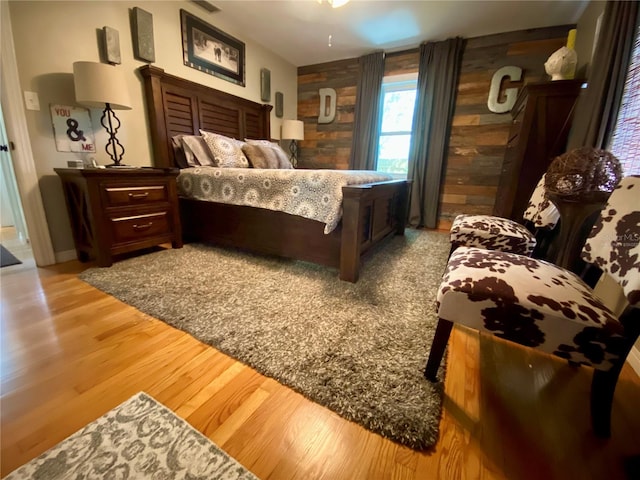 bedroom featuring light wood-type flooring and wooden walls