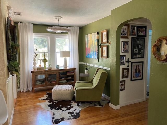 living area with a textured ceiling and light hardwood / wood-style flooring