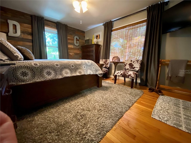 bedroom with hardwood / wood-style flooring and wood walls