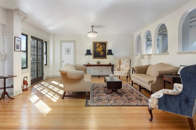 living room featuring french doors, an inviting chandelier, and light hardwood / wood-style flooring