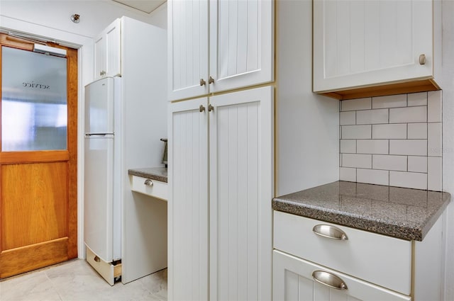 kitchen featuring white cabinets, white fridge, and tasteful backsplash