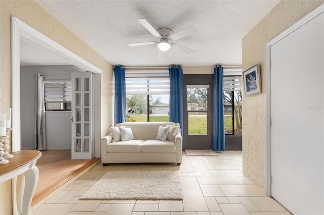 living area with ceiling fan and a textured ceiling