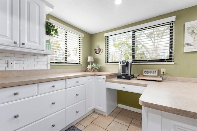 kitchen featuring white cabinets, light tile patterned floors, built in desk, and a wealth of natural light