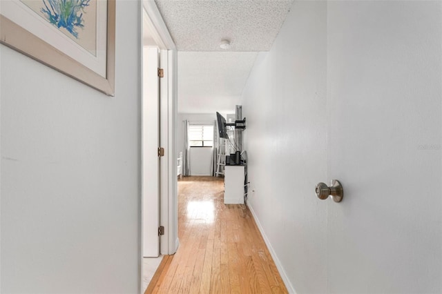 corridor featuring a textured ceiling and light wood-type flooring