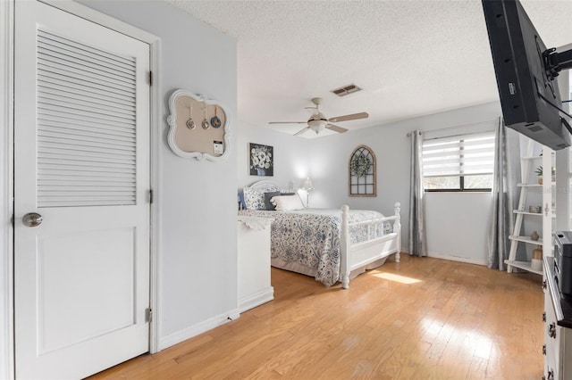 bedroom with ceiling fan, light hardwood / wood-style flooring, and a textured ceiling