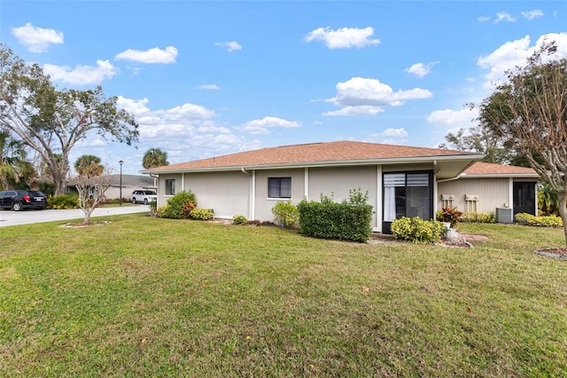 view of front of house with central AC and a front lawn