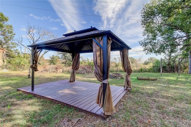 view of yard with a fire pit, a gazebo, a wooden deck, and fence